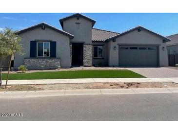 Charming single-story home featuring desert landscaping, a two-car garage, and a stone-accented facade at 16035 W Questa Dr, Surprise, AZ 85387