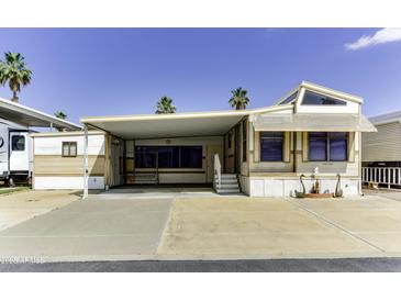 Charming mobile home exterior with carport, low maintenance yard, and sunny desert landscape at 17200 W Bell Rd # 47, Surprise, AZ 85374