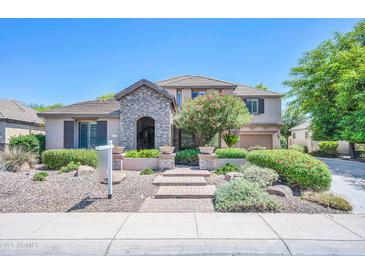 Charming two-story home features a stone archway, lush landscaping, and a welcoming entryway at 2383 E Zion Way, Chandler, AZ 85249