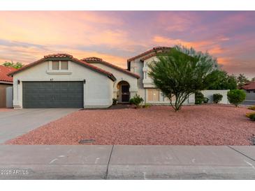 Charming single-Gathering home featuring a well-kept lawn and a gray garage door at sunset at 47 W Calle Monte Vis, Tempe, AZ 85284