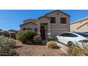 Charming home with a well-maintained front yard, red shutters, and a Tesla in the driveway at 4730 N 111Th Ln, Phoenix, AZ 85037