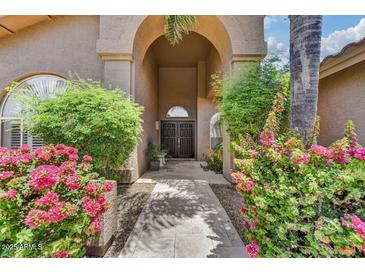 Inviting front entrance with double doors, arched entryway, and colorful landscaping in a desert climate at 7418 E Black Rock Rd, Scottsdale, AZ 85255