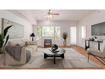 Bright living room featuring a fireplace, ceiling fan, and large windows providing ample natural light at 16 W Encanto Blvd # 26, Phoenix, AZ 85003
