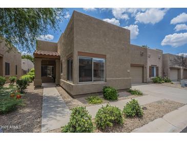Charming single-story home features a textured facade, desert landscaping, and a private garage at 1650 S Crismon Rd # 63, Mesa, AZ 85209
