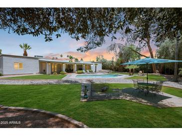 Beautiful backyard featuring a well-maintained lawn, patio, pool, and lounge area, perfect for outdoor enjoyment at 6911 E Thunderbird Rd, Scottsdale, AZ 85254