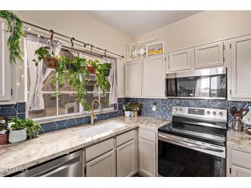Bright kitchen features hexagon tile backsplash, granite countertops, and a stainless steel oven range at 1633 E Lakeside Dr # 156, Gilbert, AZ 85234