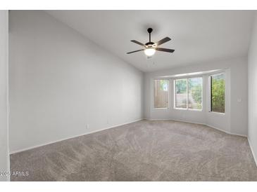 Spacious carpeted bedroom featuring a ceiling fan and natural light from large windows at 19530 N 84Th Ave, Peoria, AZ 85382