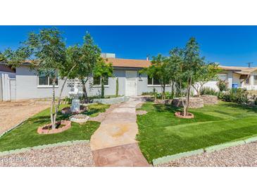 Charming front yard with lush lawn, fountain, mature trees, and welcoming walkway to the front door at 2908 N 54Th Dr, Phoenix, AZ 85031