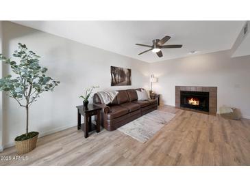 Comfortable living room featuring a fireplace, ceiling fan and a brown leather sofa at 850 S River Dr # 1047, Tempe, AZ 85281