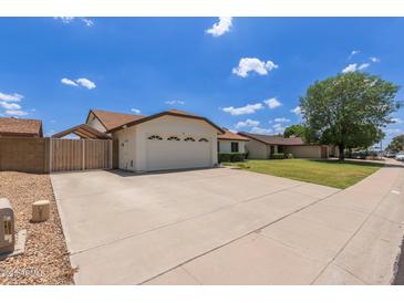Charming single-story home with a two-car garage, well-maintained lawn, and a large driveway on a sunny day at 19 W Wickieup Ln, Phoenix, AZ 85027