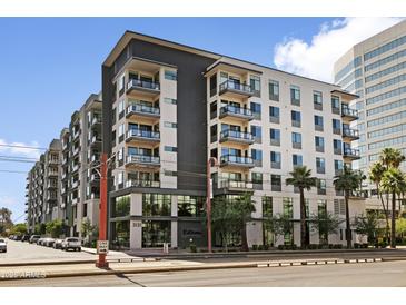 Modern apartment building with gray and white facade, balconies, and manicured landscaping on a sunny day at 3131 N Central Ave # 3009, Phoenix, AZ 85012