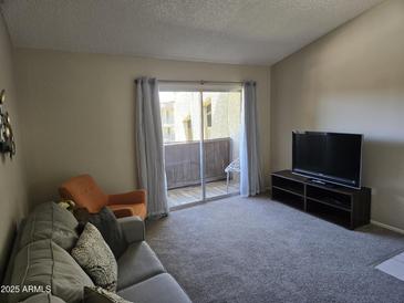 Bright living room with plush carpet and a sliding door to the balcony for natural light at 461 W Holmes Ave # 360, Mesa, AZ 85210