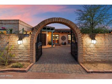Inviting entrance to a Spanish-style home with a brick archway and charming desert landscaping at 8035 E Paraiso Dr, Scottsdale, AZ 85255