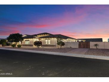 Beautiful single-story home with desert landscaping and warm exterior lighting at dusk at 9445 W Monte Lindo --, Peoria, AZ 85383