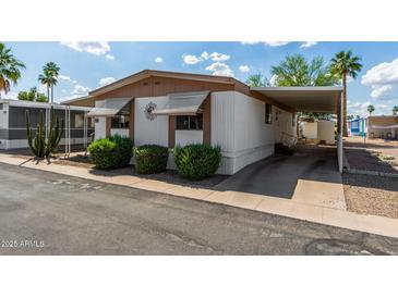 Cozy mobile home with awnings, carport, landscaping, and a paved driveway at 9501 E Broadway Rd # 168, Mesa, AZ 85208