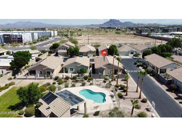 Beautiful aerial view of desert homes with a community pool, solar panels, and mountain backdrop at 5815 E Nora St, Mesa, AZ 85215