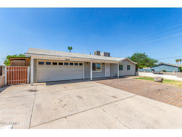 Charming home featuring a spacious driveway and a two-car garage, set beneath a clear blue sky at 7047 W Almeria Rd, Phoenix, AZ 85035