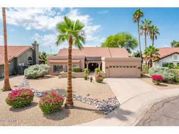 Charming single-story home with desert landscaping, mature palm trees, and a two-car garage at 8977 E Ludlow Dr, Scottsdale, AZ 85260