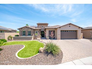 Charming stone and stucco home with a manicured lawn, paved driveway, and a two-car garage at 16772 W Cypress St, Goodyear, AZ 85395