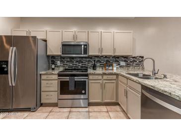 This kitchen features stainless steel appliances, tile backsplash, granite countertops, and light cabinetry at 205 N 74Th St # 166, Mesa, AZ 85207