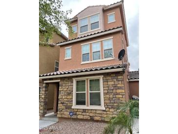 Charming two-story home featuring a stone facade, neutral stucco, a tiled roof, and an ADT security system at 2118 N 77Th Ln, Phoenix, AZ 85035