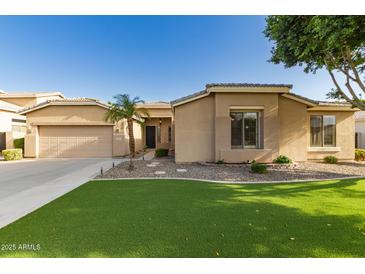Charming single story home with a two car garage, green grass, desert landscaping, and well kept yard at 2183 W Hawken Way, Chandler, AZ 85286