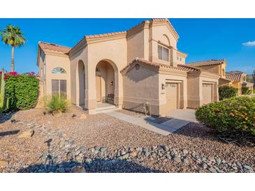 Charming two-story stucco home featuring a well-manicured desert landscape, tile roof, arched entry, and a two-car garage at 24433 N 75Th St, Scottsdale, AZ 85255