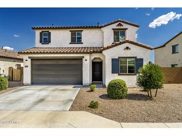 Inviting two-story home with a gray garage door, tile roof, and low-maintenance desert landscaping at 40445 W Bravo Dr, Maricopa, AZ 85138