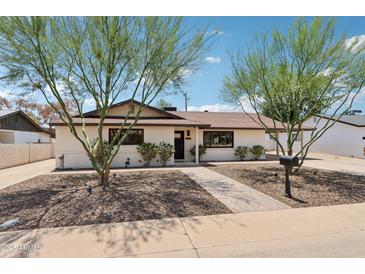 Charming single-story home featuring desert landscaping, a brick walkway, and a well-maintained front yard at 7049 E Latham St, Scottsdale, AZ 85257
