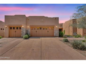 Inviting home exterior features a three car garage with stone accents and desert landscaping at 13450 E Via Linda -- # 2022, Scottsdale, AZ 85259