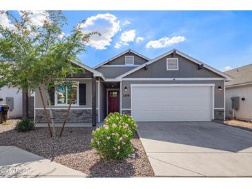 Charming single-story home featuring a red front door, a two-car garage, and desert landscaping at 5808 S 12Th Ln, Phoenix, AZ 85041
