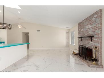 Bright living room featuring a brick fireplace, white marble floors, and modern lighting at 643 W Medina Ave, Mesa, AZ 85210