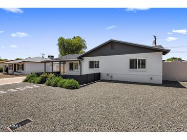 Charming home featuring a crisp white exterior, complemented by a gravel landscape, and a covered porch area at 7707 E Earll Dr, Scottsdale, AZ 85251