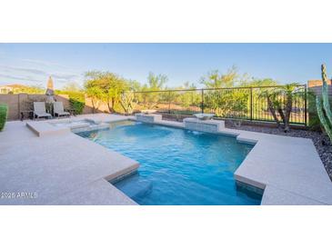 Gorgeous backyard pool with unique water features, surrounded by lush desert landscaping at 13719 W Amberwing St, Peoria, AZ 85383