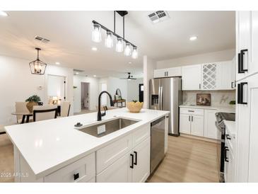 Bright kitchen boasts white cabinets, stainless steel appliances, quartz countertops and updated lighting at 1425 E Diamond St, Phoenix, AZ 85006