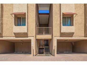 View of building exterior with garages and staircases leading to the units above at 151 E Broadway Rd # 103, Tempe, AZ 85282