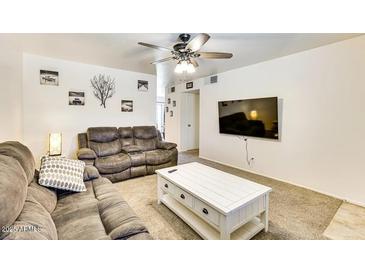 Spacious living room featuring neutral colors, plush sofas, ceiling fan, and large screen TV at 3553 W El Camino Dr, Phoenix, AZ 85051