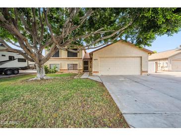 Charming home with a large tree shading the front yard and a two-car garage at 608 E Arabian Ct, Gilbert, AZ 85296