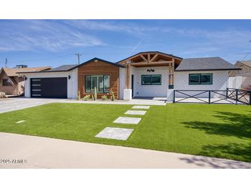 Charming single-story home with modern black garage and manicured front yard at 8318 E Sells Dr, Scottsdale, AZ 85251