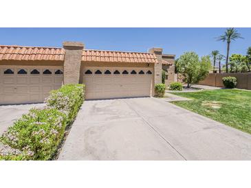 Beige home featuring 2-car garage with tile roof and well-maintained landscaping at 9196 E Evans Dr, Scottsdale, AZ 85260