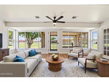 Bright living room features large windows, hardwood floors, ceiling fan, neutral paint, and comfortable seating at 10839 W Peoria Ave, Sun City, AZ 85351
