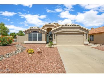Charming single-story home featuring a low-maintenance desert landscape and a two-car garage at 20443 N 97Th Ave, Peoria, AZ 85382