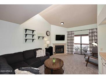 Inviting living room featuring a fireplace, balcony access, and soaring vaulted ceilings at 205 N 74Th St # 248, Mesa, AZ 85207