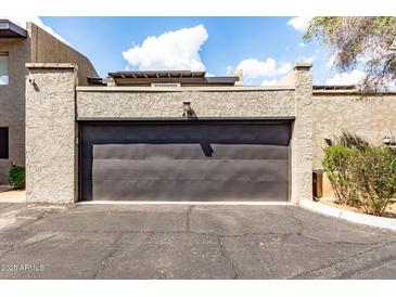 Two car garage with a black door and stucco siding, with an attached front parking area at 618 E Manzanita Pl, Phoenix, AZ 85020