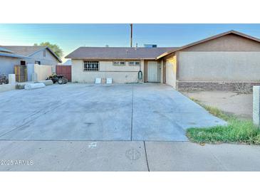 Home featuring a large driveway, small lawn, and front entrance at 7940 W Avalon Dr, Phoenix, AZ 85033