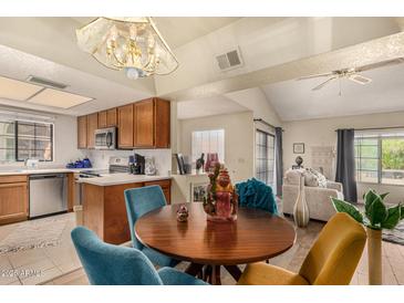Open dining area features a chandelier, wood table, and blue upholstered chairs next to the kitchen and living room at 839 S Westwood -- # 287, Mesa, AZ 85210