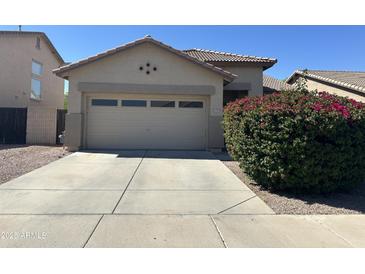 Charming single story home featuring an attached garage and a tidy front yard landscape at 11921 W Madison St, Avondale, AZ 85323