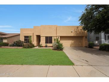 Attractive tan home features a two-car garage, green lawn, and desert landscaping at 2229 S 82Nd Ln, Phoenix, AZ 85043