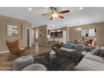 Inviting living room featuring a modern ceiling fan, tile flooring, and an open-concept layout to the kitchen and dining area at 16525 W Tranquility Ln, Surprise, AZ 85387