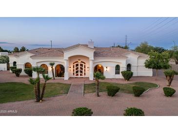 Stunning single-story home boasts arched windows, a decorative front door, and mature landscaping at 3126 E Fruitvale Ct, Gilbert, AZ 85297